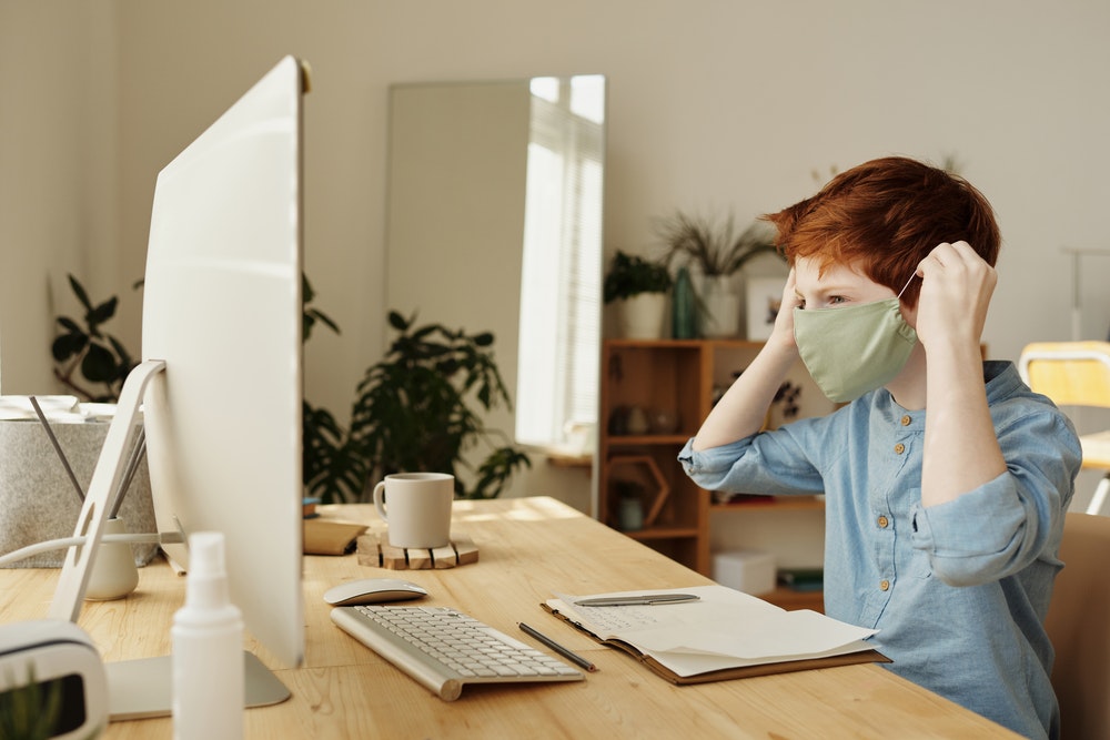 Boy wearing a face mask in front of a computer