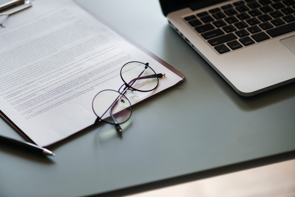Documents on the table next to a laptop 